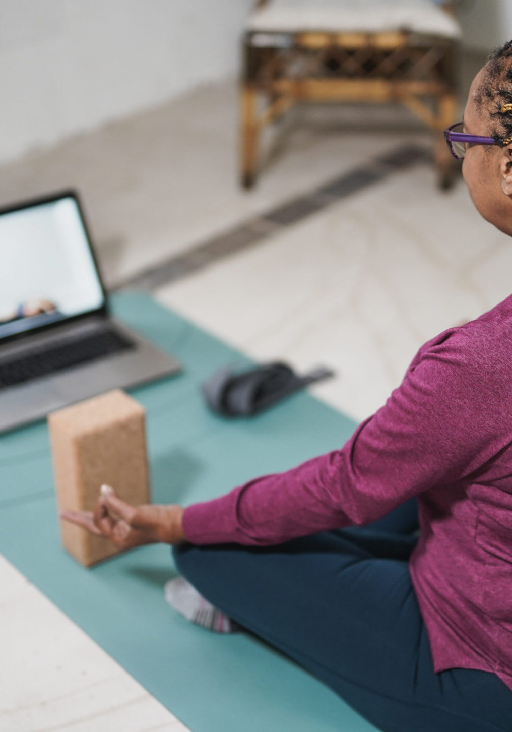 African senior woman doing yoga at home with laptop - Meditation, mindfulness and health care